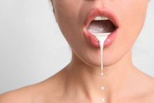 Young Woman With White Liquid Dripping From Her Mouth On Light Background. Erotic Concept