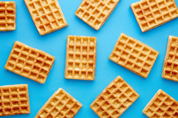 Fresh waffles pattern isolated on a blue background viewed from above. Top view