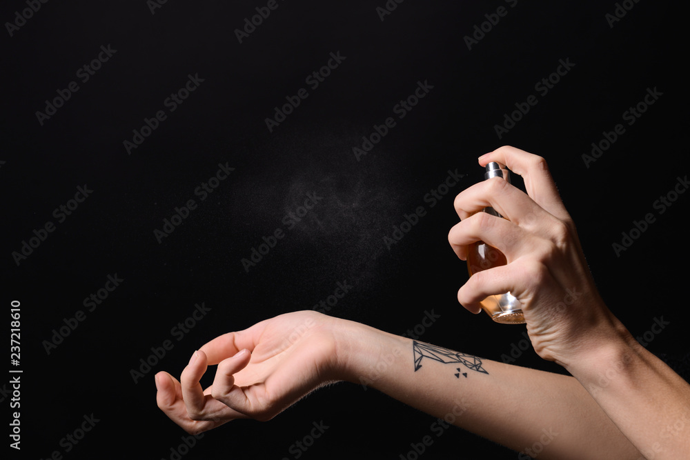 Woman with bottle of perfume on dark background