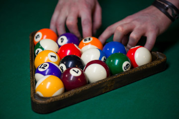 Wall Mural - Sport billiard balls set arranged in shape of triangle on green billiard table in pub. Players are ready for the first hit of the round to start the billiard game.