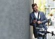 Portrait of young businessman with his bicycle looking at phone.