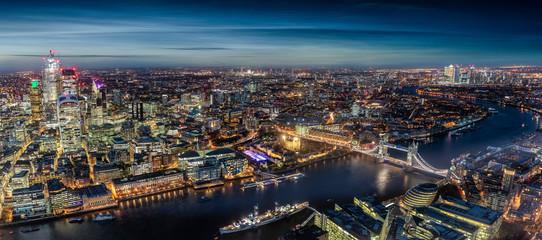 Fototapete - Weites Panorama der hell beleuchteten Skyline von London entlang der Themse am Abend, Großbritannien