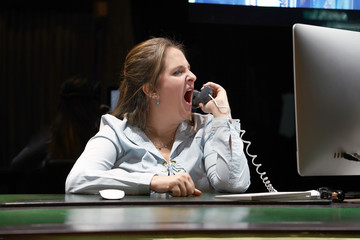 A woman-reception swears with the client of the hotel by phone. A woman is shouting into the phone's phone. Funny facial expressions, emotions, reaction of perception, stress, gilding, nerves.