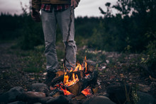 Man Poking Campfire At Dusk