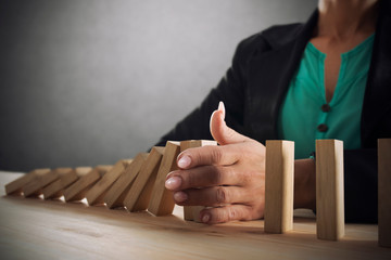 Businesswoman stops a chain fall like domino game. Concept of preventing crisis and failure in business