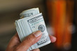 © Monica Murphy/Stocksy - Hand holds roll of 100 dollar bills