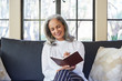 © Trinette Reed/Stocksy - Mature woman with grey hair journaling in living room