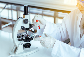 Scientist women working putting medical chemicals sample on microscope at laboratory