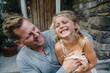 © Rob and Julia Campbell/Stocksy - Dad tickling daughter and laughing outside house