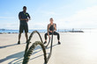 © Guille Faingold/Stocksy - Sportswoman doing exercise with ropes with personal trainer.