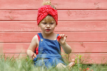 Little girl is eating sweet strawberries on a sunny day.