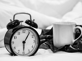 alarm clock and coffee cup on the bed