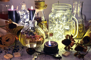 Still life with luminous bottles, paper scrolls, runes, seeds and black candle. Magic gothic ritual. Wicca, esoteric and occult background 