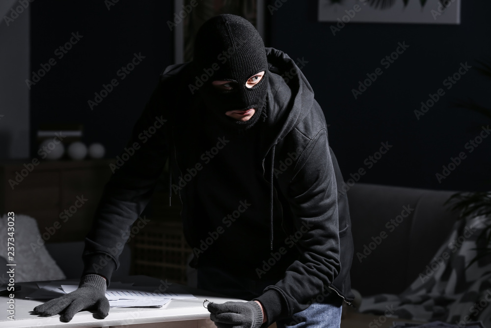 Male thief looking for valuables indoors