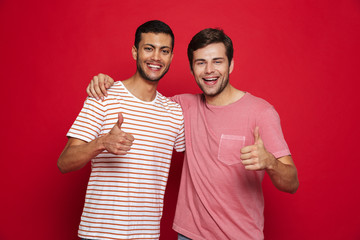 Canvas Print - Two cheerful young men standing isolated over red