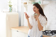 © Elena Kharichkina - Young happy woman drinking coffee on the kitchen in the morning.