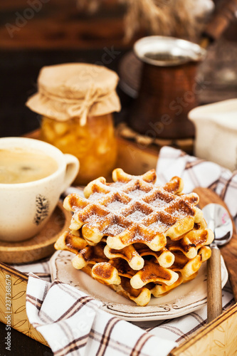 Fotografía Breakfast with belgian waffles, jam and coffee on tray, rustic background