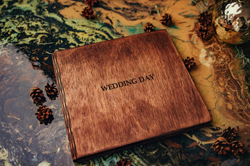 Wall Mural - Photobook of wood. Wedding photo album with a wooden cover is on an unusual background with cones