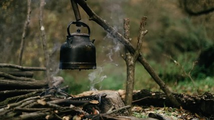 with knife, water bottle and titanium mug near the fire outdoors. bushcraft, adventure, travel, tour