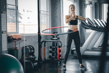 Beautiful Caucasian Young Woman Doing Hula Hoop In Step Waist Hooping Forward Stance. Young Woman Doing Hula Hoop During An Exercise Class In A Gym. Healthy Sports Lifestyle, Fitness, Healthy Concept.