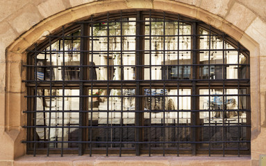 Old castle's arched barred glassed window with mirrored reflection