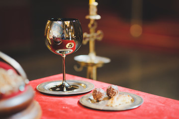 Poster - glass of red wine on wooden table in church