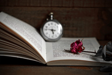 Withered rose, antique clock and book