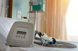 CPAP machine components..CPAP machine mask and tube on white bed cover on bed of hospital with blurred   curtain background.
