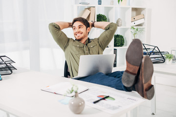 Smiling businessman relaxing on chair with hands on head