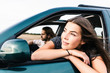 © Westend61 - Smiling young woman leaning out of car window