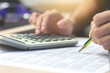 © manoonpan - Close-up Businessman accountant hand holding pencil working on calculator to calculate financial data report. business financial concept.