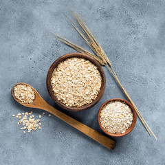 Rolled oats or oat flakes in wooden bowl, top view