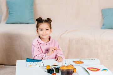 cute happy child painting pictures and smiling at camera