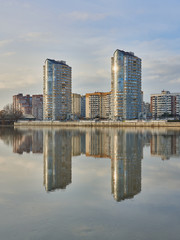 Two skyscrapers on the background of the old city of Krasnodar in early December are reflected in the Kuban River at sunset. Two towers - two worlds.