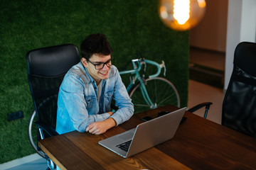 Wall Mural - Young employee using laptop in modern office