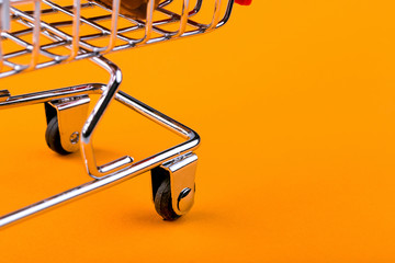 Wall Mural - shopping trolley on orange background, shopaholic concept