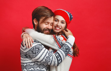 Wall Mural - happy couple   man and   woman in christmas hats on red background