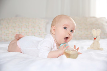 Canvas Print - Pretty baby lying with bottle on bed at home