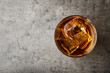 Golden whiskey in glass with ice cubes on table, top view. Space for text