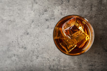 Golden Whiskey In Glass With Ice Cubes On Table, Top View. Space For Text