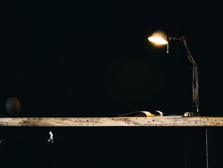 wooden table in solid oak and desk lamp on a dark background.