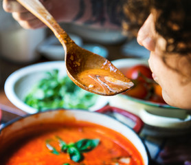 Wall Mural - Woman tasting a tomato soup in the kitchen