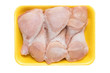 Frozen chicken legs in a yellow tray isolated on a white background. Raw chicken meat.