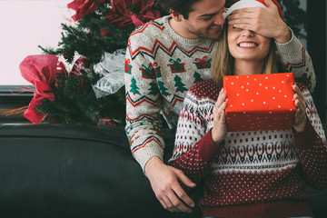 Wall Mural - Young man surprise beloved woman with Christmas gift