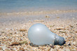 Pollution : Beach / Sea pollution. Light bulb on the sea beach. Selective focus with copy space