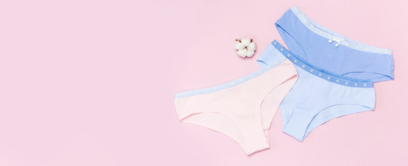 Female pastel cotton set panties and cotton flower on pink background top view flat lay with copy space for text. Fashion blog, Colorful women's natural underwear, advertising, shopping concept.