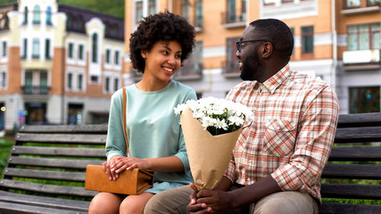 Beautiful young woman meeting boyfriend on first date, man presenting flowers