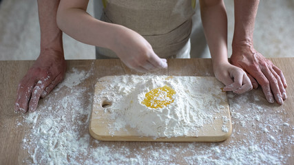 Grandchild and granny cooking traditional cake, little girl adding flour, recipe