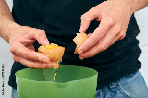 Fotografía Close-up man's hands break the egg and separate the white from the yolk