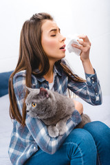 Wall Mural - young woman with allergy holding facial tissue and british shorthair cat